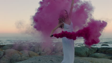 woman-holding-pink-smoke-bomb-dancing-on-beach-in-early-morning-celebrating-creative-freedom