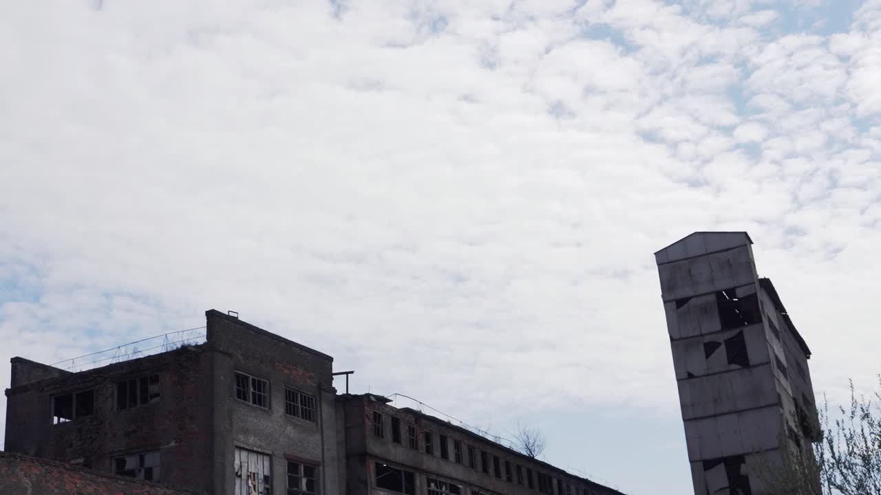 Abandoned and destroyed building of the old factory. Post-apocalyptic landscape. Broken windows, cracked brick and concrete walls. Consequences of the war