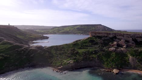 Drone-footage-flying-above-cliffs-and-azure-water-in-Malta,-showcasing-stunning-coastal-views