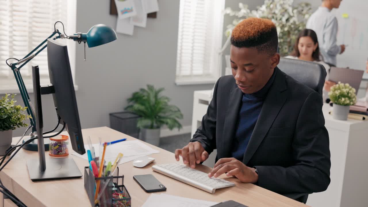 homem elegante trabalhando em um escritório menino está sentado atrás da mesa na frente do computador, verificando a correção de papel e documentos eletrônicos, inserindo dados no sistema tocando os dedos no teclado