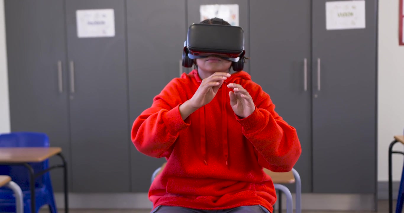 African American youth sitting in classroom chair, VR starting reaching pinching content to learn