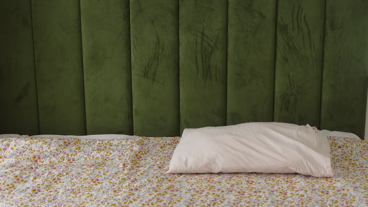 interior del dormitorio con cabecera verde y ropa de cama floral