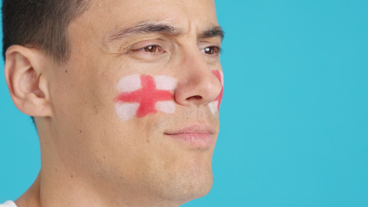 Happy man with english flag painted on face looking away