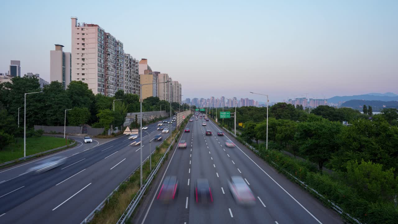 Time-lapse of busy Gangbyeonbuk-ro highway in Seoul at sunset, with fast-moving traffic and city skyline
