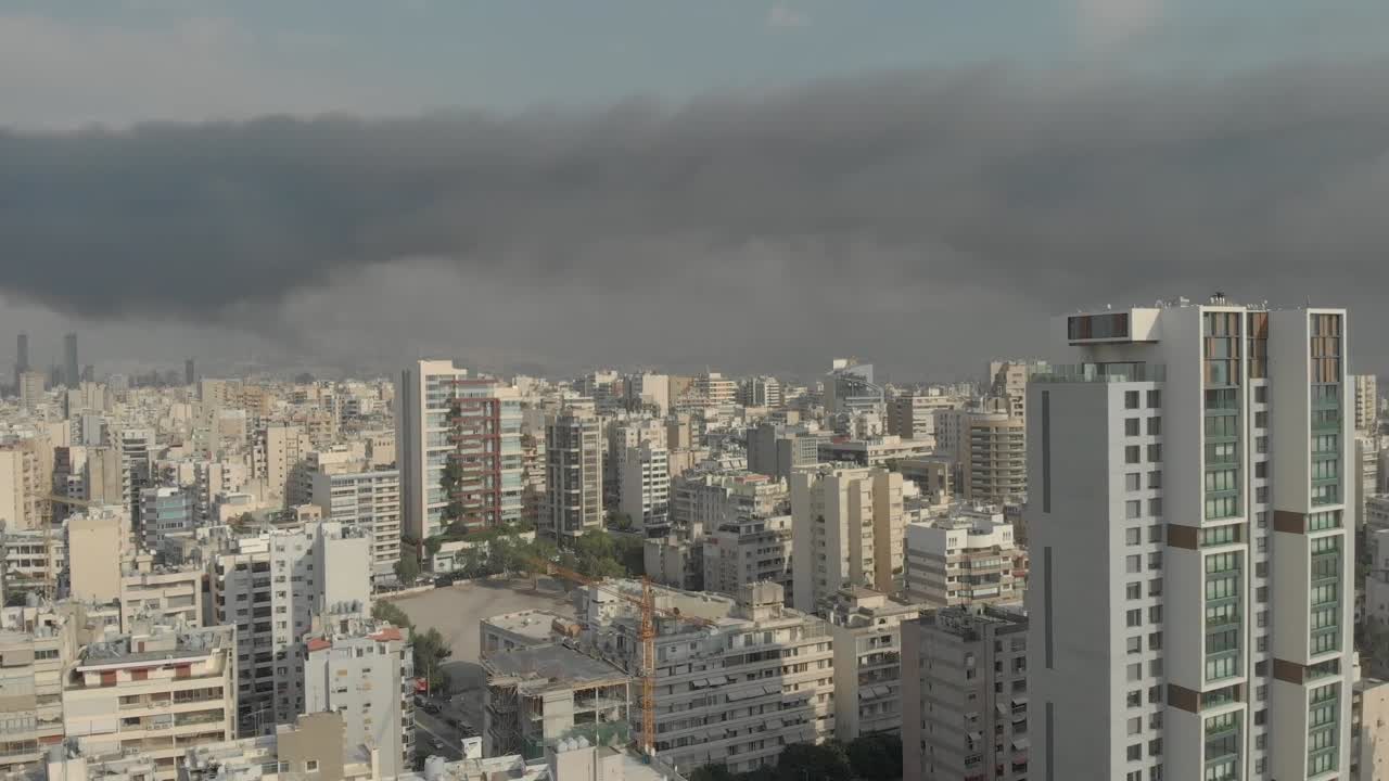 Aerial footage showing a large black smoke cloud spreading over Beirut. It covers a wide area of the city. The footage captures the smoke's movement and density as it drifts across urban areas
