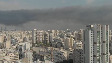 aerial footage showing a large black smoke cloud spreading over beirut. it covers a wide area of the city. the footage captures the smoke's movement and density as it drifts across urban areas