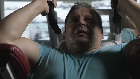 man exercising hard on strength training machine in the gym