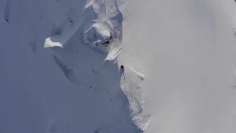 Drone-shot-of-snowboarder-walking-on-dangerous-ridge-in-Austria