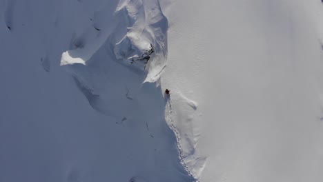 drone shot of snowboarder walking on dangerous ridge in austria