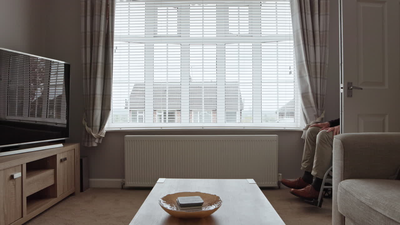 Senior man in wheelchair looking out window with caregiver