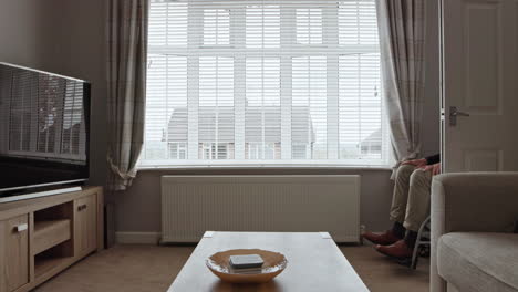 senior man in wheelchair looking out window with caregiver