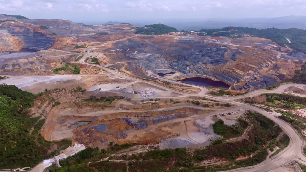 Extensive Barrick Gold open-pit mine in Cotui, industrial landscape of gold and silver extraction, Dominican Republic. Aerial forward