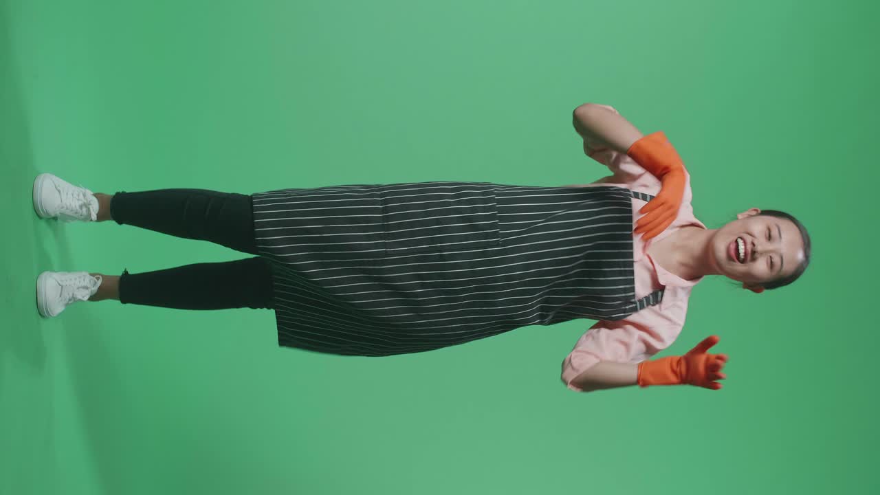 녹색 스크린 스튜디오에 서서 춤을 추는 즐거운 아시아 여성 집주인의 몸