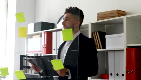 businessman in suit coat working near glass wall in office