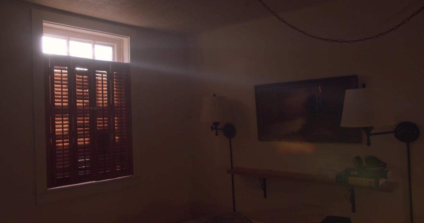 Rayos de luz brillantes se filtran por las persianas hacia una habitación acogedora