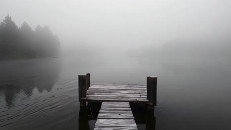 a wooden dock in the middle of a foggy lake