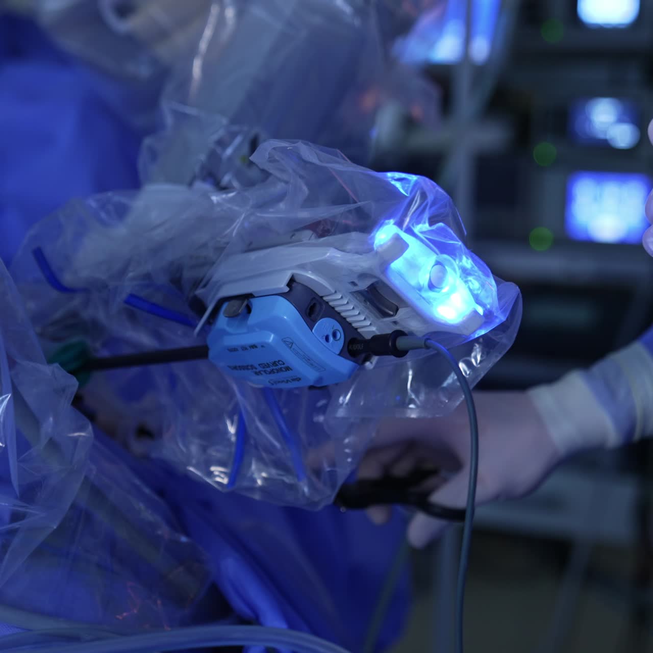 Unrecognized doctor stands in the operative field of Da Vinci robot. Surgeon holds the instrument under the moving manipulator arm of equipment