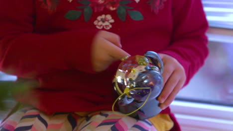 a sweet little girl plays with a christmas music box ornament