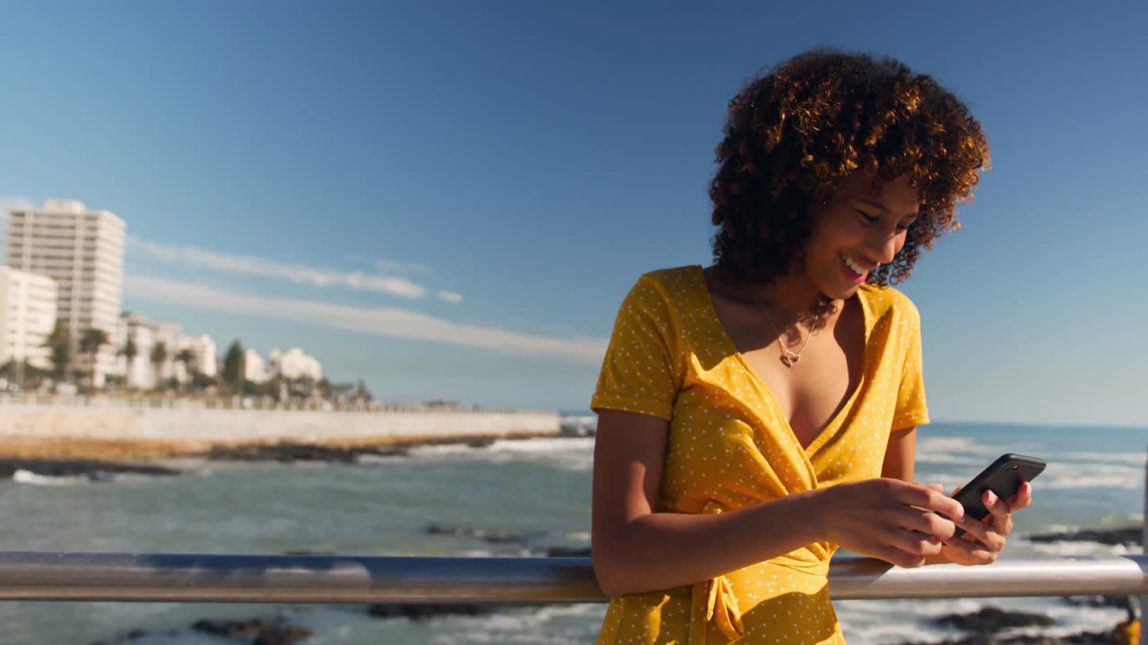 Woman smiling and using phone at beach