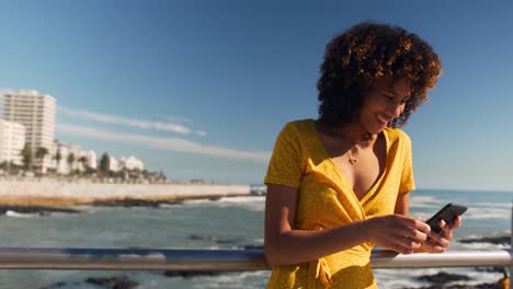 mujer sonriendo y usando el teléfono en la playa