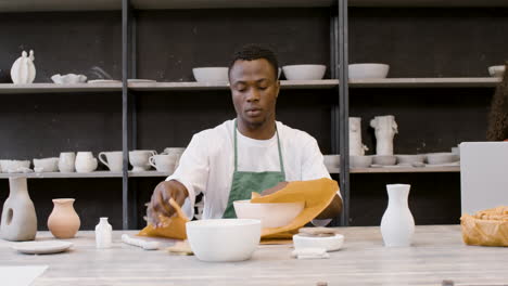 young man packaging handicraft ceramics with paper in the pottery shop