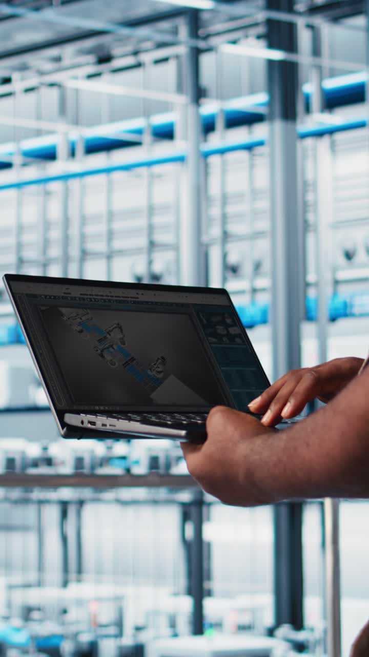 Vertical video Smart factory engineer designs robotic machines using laptop CAD software