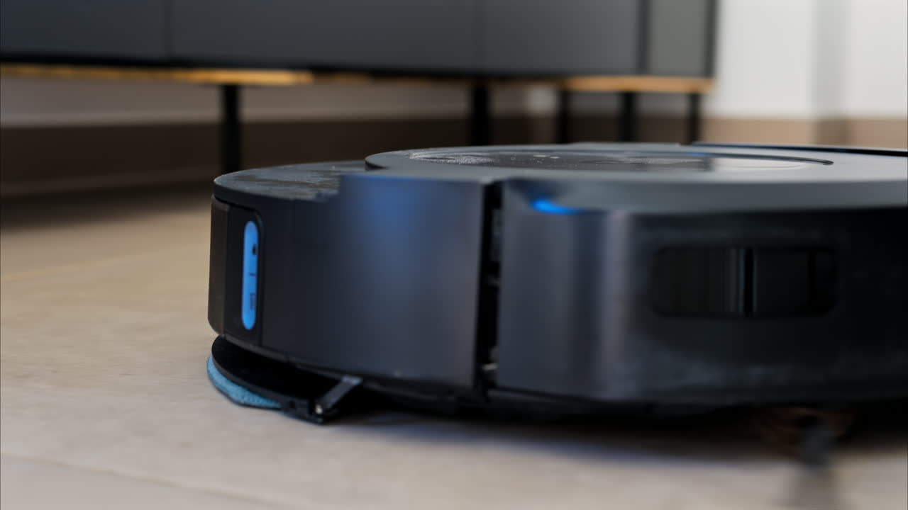 Close up of a black robot vacuum cleaner moving and rotating on the floor tiles