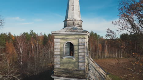 rising drone shot captures historic countryside church surrounded by fields, forests in autumn beauty