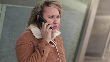 mujer madura seria hablando en el teléfono inteligente al aire libre