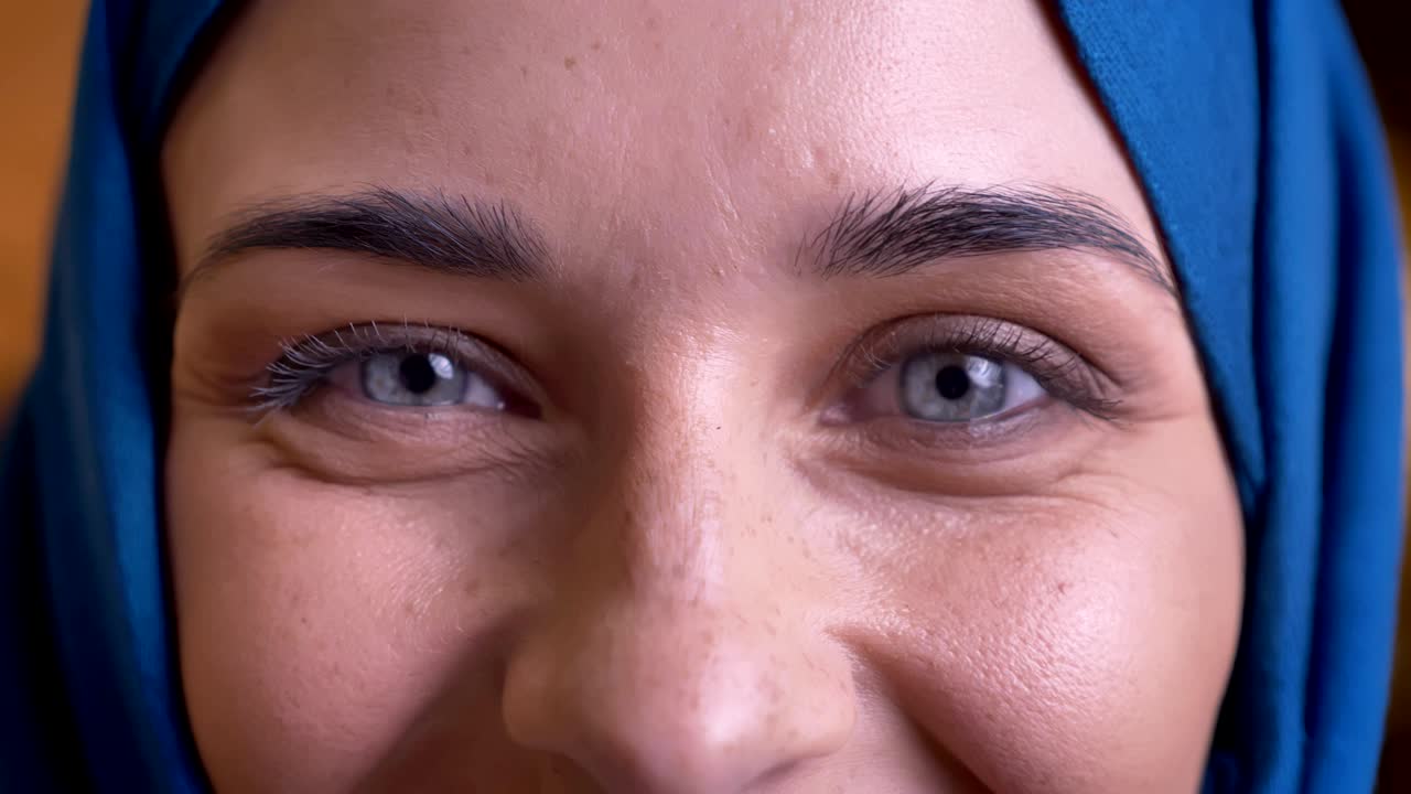 retrato en primer plano de una mujer musulmana adulta en hijab mirando directamente a la cámara con sus hermosos ojos grises y con expresión facial sonriente