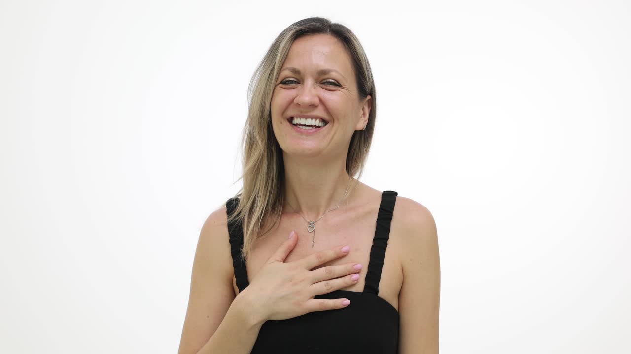 Mujer sonriente con la mano en el pecho sobre un fondo blanco