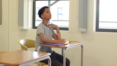 in school, boy holding pencil, attentively listening at desk