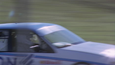 racing cars race around a track as people watch and a man waves a flag