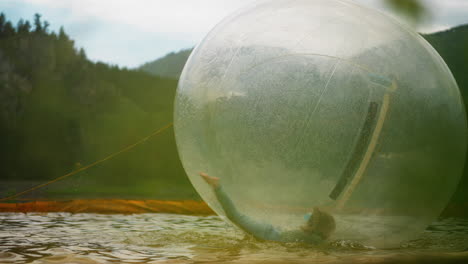 niña en edad preescolar monta una esfera de agua flotando en una pequeña piscina
