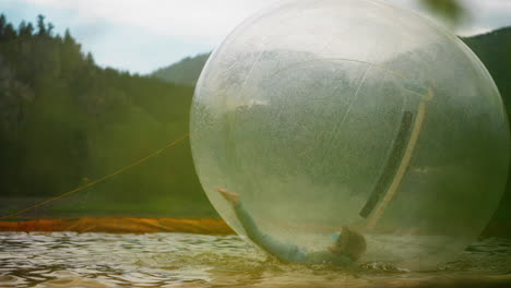 preschooler girl rides water sphere floating in small pool