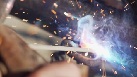 a welder uses welding electrode to connect an old metal chain to a rusted pipe - close up