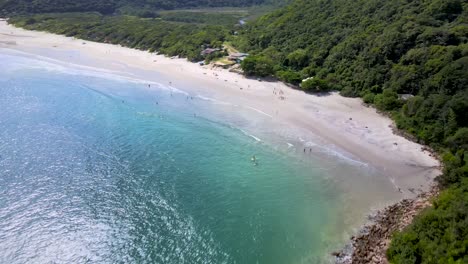 Aerial-drone-view-of-tropical-deserted-paradise-beach-with-rocky-coast-and-atlantic-forest-turquoise-blue-color-ocean-and-fishing-barocs