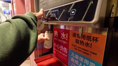 person fills cup from hot water machine