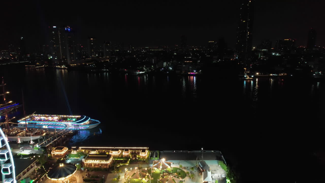 Aerial view passing the Asiatique Sky Ferris Wheel, nighttime in Bangkok, Thailand
