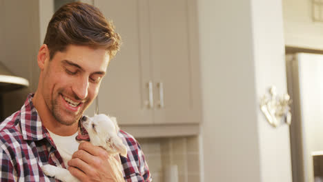 smiling young man holding pet in his arms in the kitchen 4k 4k