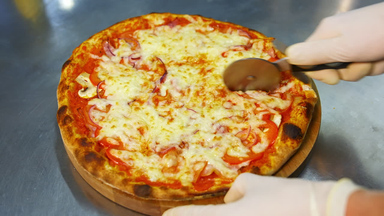 Chef che taglia pizza appena sfornata. Primo piano della mano di un pizzaiolo che taglia la pizza in cucina.