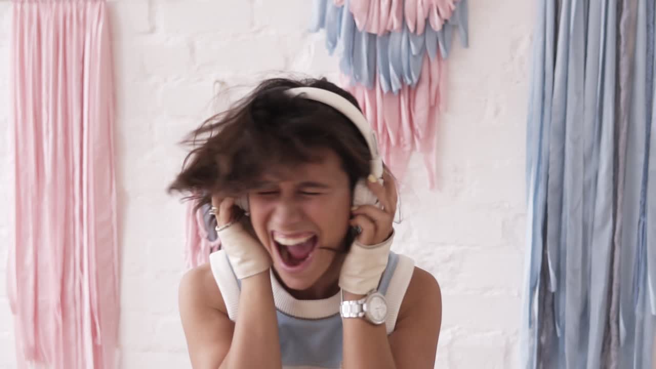 백인 여성이 헤드폰으로 음악을 들으면서 비명을 지르고 머리를 흔들고 있습니다. 망쳤습니다. 느린 영상