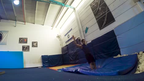 a slow motion still shot of a guy doing flips from the trampoline landing and winning having fun and working out in 60fps