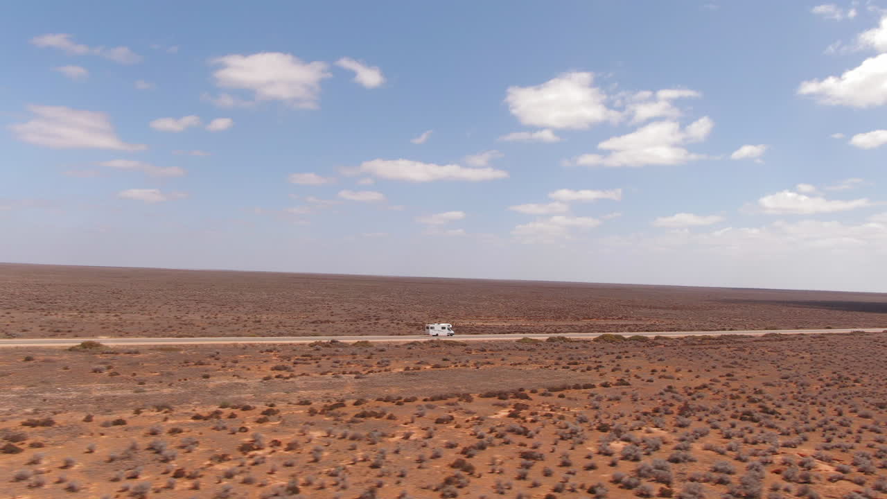 황량한 환경에서 빈 긴 직선 도로를 운전하는 캠퍼밴