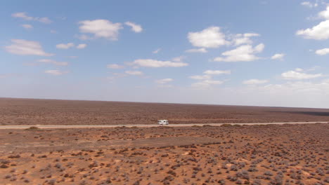 campervan driving on an empty long straight road in a barren environment