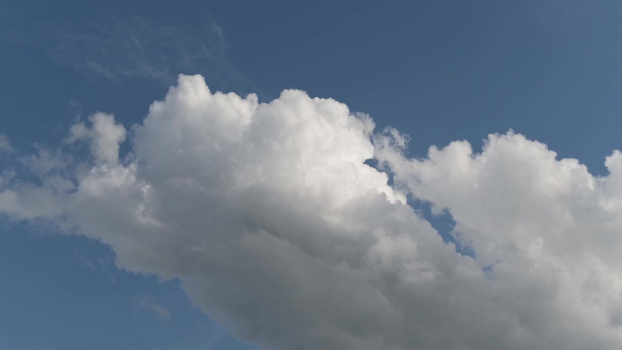Nuvole bianche scivolano in diagonale dall'angolo inferiore destro verso l'angolo superiore sinistro attraverso un cielo azzurro e limpido. Il movimento in timelapse crea uno sfondo atmosferico pulito e dinamico.