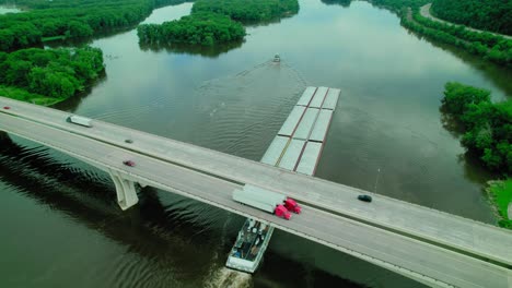 tugboat pushing barge, scow, floating platform on missisipi river in wisconsin under dresbach bridge