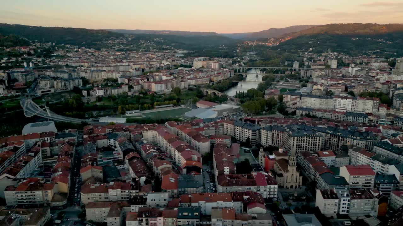 Aerial orbit establishes dense apartment buildings in Ourense Spain at sunset