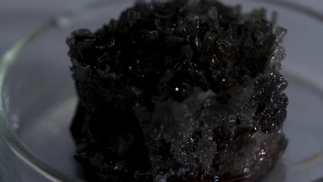 close-up of dark crystals in a petri dish