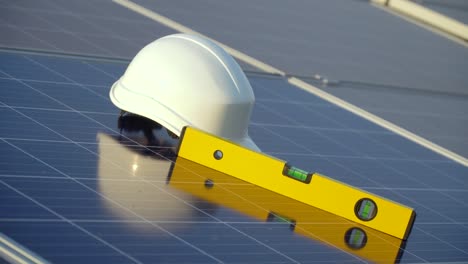 white hard hat and spirit level on solar panel. the concept of clean energy, green energy, renewable energy. photovoltaic panel